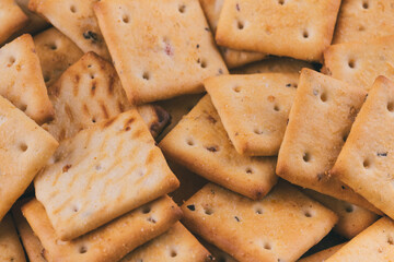 Heap of delicious spicy square crackers. Salty crackers closeup. Macro shot. Selective focus.