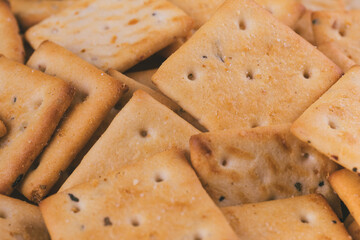 Heap of delicious spicy square crackers. Salty crackers closeup. Macro shot. Selective focus.