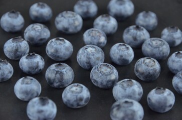 A bunch of blueberries on a black textured background, closeup, side view