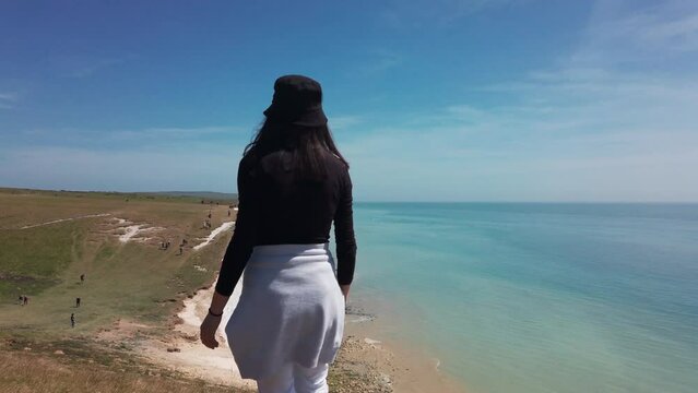 Woman tourist enjoy amazing panoramic view of Seven Sisters National park, white cliffs,beach,ocean East Sussex, England, slow motion