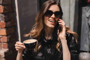 Fototapeta na wymiar Blonde woman smiling positive conversation talking to her friend using phone hand hold hot drink coffee relax casual positive emotion weekend relax routine at cafe restaurant. Girl have discussion.