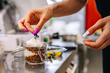 woman chef hand decorated carrot cake in a glass jar on table