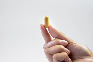 Body support with supplements, ashwagandha capsule held in hand on a white background