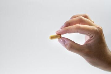Body support with supplements, ashwagandha capsule held in hand on a white background