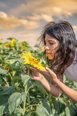 jeune femme humant un tournesol dans un champs