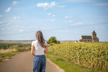 Jeune femme en jeans, sur une route de campagne au soleil se retournant