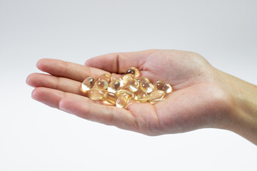 D3k2 tablets held in the hand on a white background, golden capsules, dietary supplement