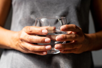 Female hands holding a glass with water, prevention of dehydration