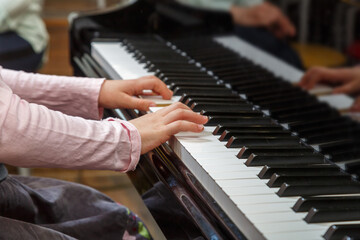 Obraz premium A child learns to play the piano in the lessons at a music school.