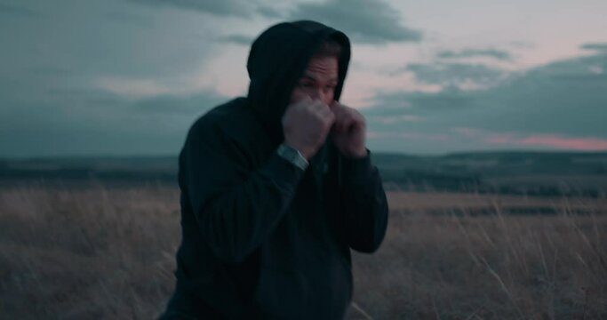 active boxer preparing for battle, martial art Slow motion Hobby, interest, self-defense, young man is fighting with fists. ready to attack. boxer in black hoodie is striking, strength power. - Powered by Adobe