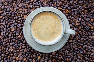 Cup with coffe on the roasted coffe beans.