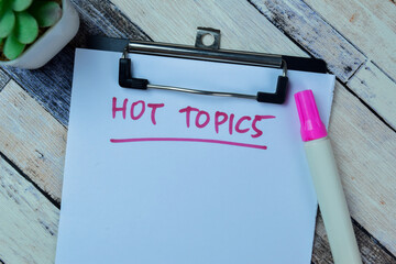 Concept of Hot Topics write on paperwork isolated on Wooden Table.