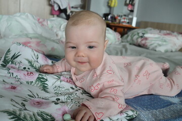 a four-month-old girl lies on a white sheet with an inscription and openwork embroidery