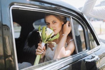 Wedding portrait, a photo of a stylish bride with a bouquet of flowers in the window of a black retro car