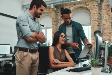 Multi ethnic team. Young afro american man pointing at digital tablet and discussing new project with his coworkers while working in modern office