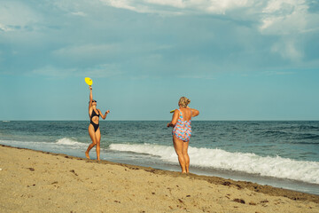 mother and daughter play mat cat on the beach in the summer afternoon