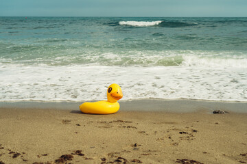 Fototapeta na wymiar lifebuoy yellow duck on the sand on the beach on a summer day