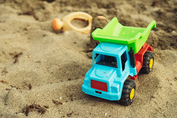 children's beach toys made of plastic on the sand near the sea trucks watering can rake