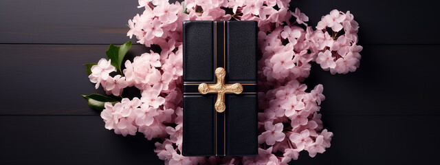 A Bible in a black leather cover with a gold cross on a wooden table with flowers. Christian religious background, banner.