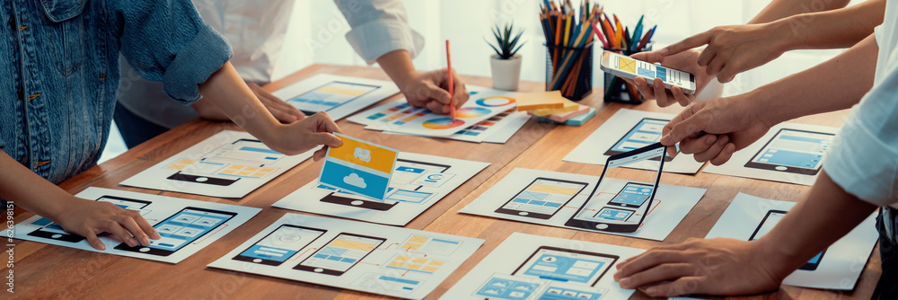 Poster Panorama shot of front-end developer team brainstorming UI and UX designs for mobile app on paper wireframe interface. User interface development team planning for user-friendly UI design. Scrutinize