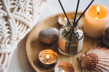 Apartment natural aroma diffusor with sea breeze fragrance. Burning candles on bamboo tray, cozy home atmosphere. Relaxation, detention zone in the living or bedroom. Stones as decor