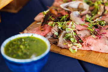 Thin sliced beef catering spread with green sauce