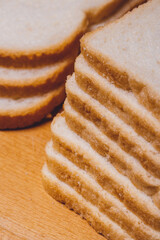 Sliced white bread with brown crust closeup on a wooden board.