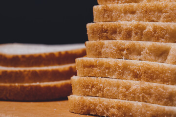 Sliced white bread with brown crust closeup on a wooden board.