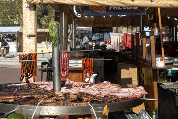 Barcelona, Catalonia, Spain - 29 March 2023: Food court, various types of fried sausages and meats in a large cauldron, vegetables as a side dish in a street market