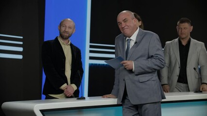 Funny charismatic host talking to the contestants during recording of a fictional morning family game show