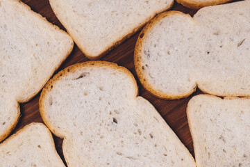 Sliced white bread with brown crust closeup on the dark wooden table. Top view