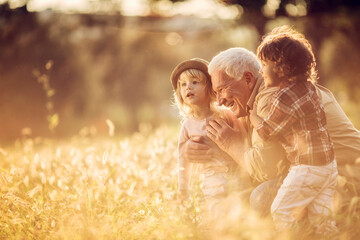 Young boy and girl spending time at the park with their grandfather