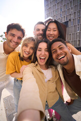Vertical selfie of a Group of happy multiracial friends having fun outdoors at the park. Diverse...
