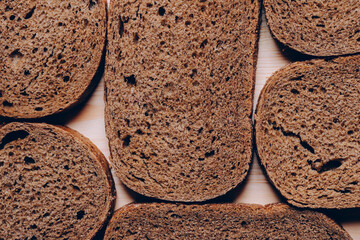 Sliced brown bread on the white wooden table. Top view