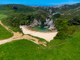 Fototapeta na wymiar Aerial view, Playa de Gulpiyuri, flooded sinkhole with inland beach near Llanes, in Asturias Northern Spain, around 100 m from Cantabrian Sea, the shortest beach in the world