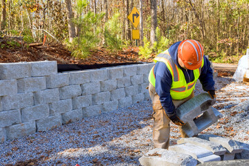 Construction worker is currently working on building retaining wall while constructing wall retaining in new property.