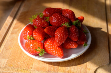 Plate with french red ripe sweet strawberries Fraises de Plougastel, harvested in France