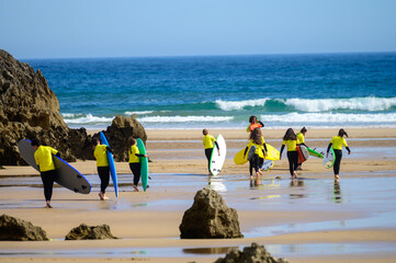 Young surfers train on Playa de Palombina Las Camaras in Celorio, Green coast of Asturias, North Spain with sandy beaches, cliffs, hidden caves, green fields and mountains