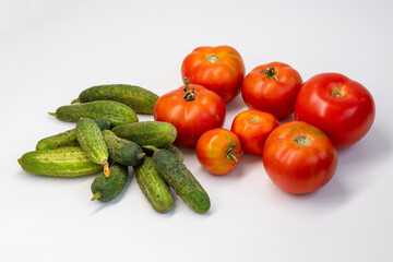 Fresh cucumbers and tomatoes on a white background. Plenty of fresh vegetables, healthy veggie food.