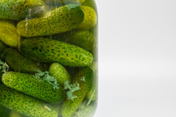 A jar of pickled cucumbers close-up on a white background. Healthy food, pickled cucumbers in a jar. Detailed texture of cucumbers in a jar.
