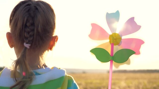 young child joyfully playing with pinwheel toy park, wind blows gently. happy family moment captures dreams innocence childhood. baby girl silhouette adds touch magic enjoystoy under warm glow setting
