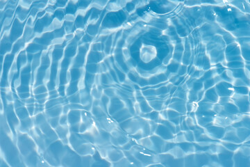 Blue water with ripples on the surface. Defocus blurred transparent blue colored clear calm water surface texture with splashes and bubbles. Water waves with shining pattern texture background.