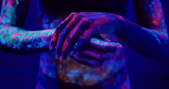 woman with painted hands palms rubbing them. female hands with fluorescent art isolated on dark blue background, minimal fashion background, body part, close-up photo.
