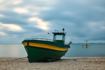 Naklejka na ściany i meble Morning landscape over the Polish Baltic Sea. Fishing boat on the beach in Gdynia Orlowo, Poland. Photo with long exposure effect.