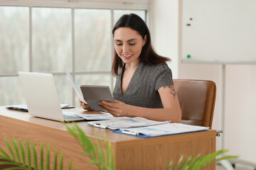 Female accountant working with document and calculator at table in office
