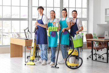 Young janitors with cleaning supplies in office