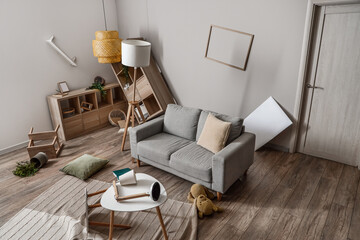 Fototapeta na wymiar Sofa with tables and shelving units in messy living room