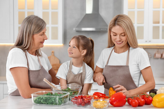 Three generations. Happy grandmother, her daughter and granddaughter cooking together in kitchen