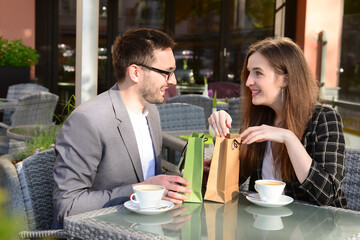 Young man giving present for his girlfriend in restaurant on sunny spring day