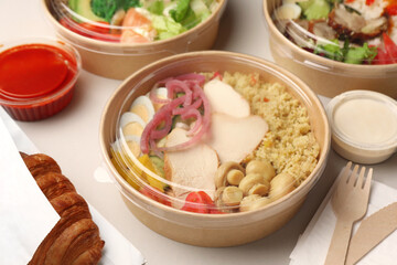 Tasty food in containers with wooden knife and fork on light grey table, closeup